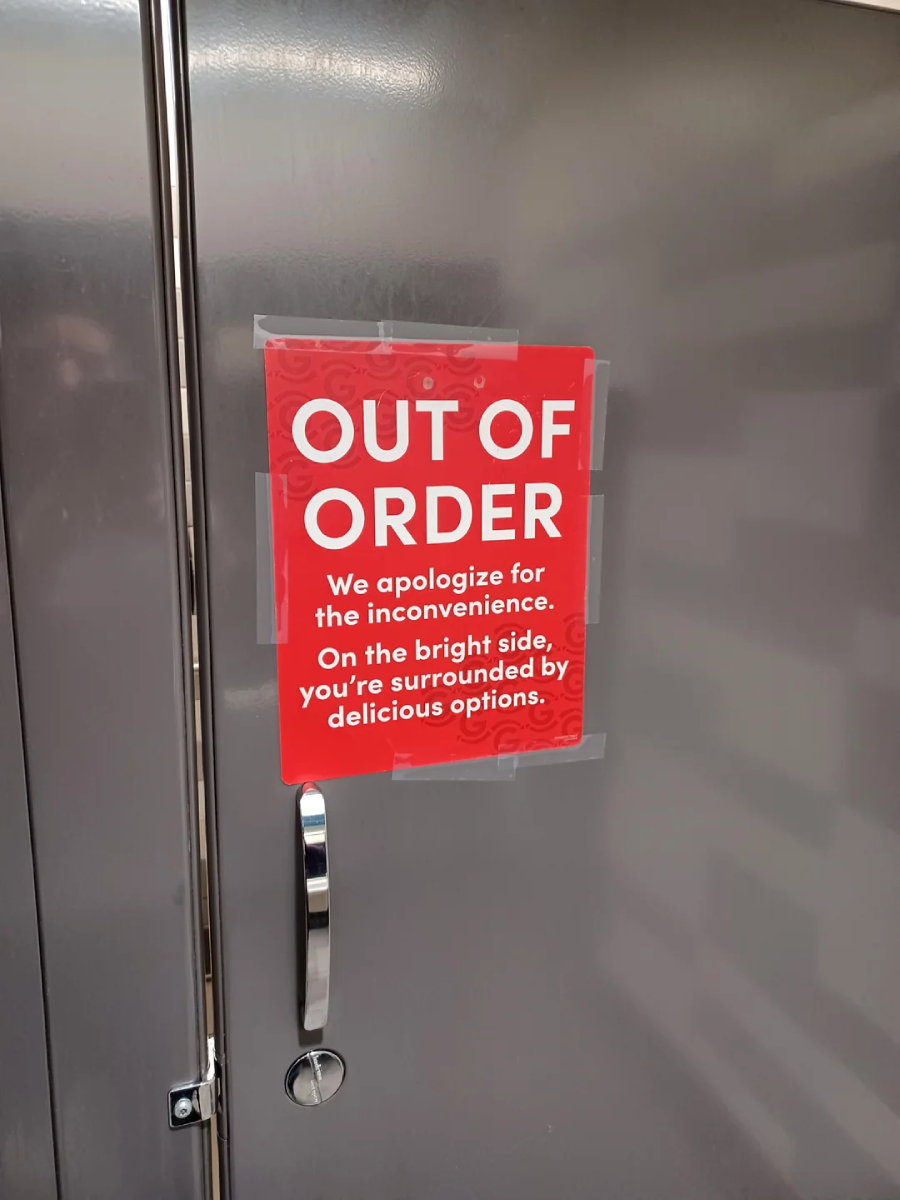 A red sign taped to a metallic door reads, "OUT OF ORDER. We apologize for the inconvenience. On the bright side, you’re surrounded by delicious options.