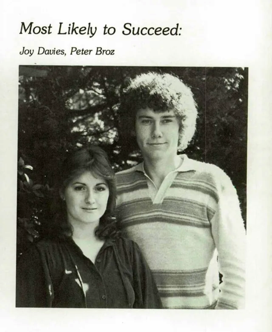 Black-and-white yearbook photo of two young adults standing close together and smiling slightly. Above them, text reads "Most Likely to Succeed: Joy Davies, Peter Broz.