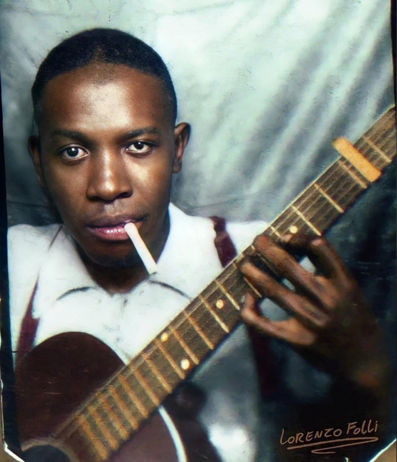 A young man with short hair holds an acoustic guitar, fingers on the fretboard, and has a cigarette in his mouth. He wears a white shirt with suspenders. The image has a vintage feel, with the name "Lorenzo Folli" in one corner.