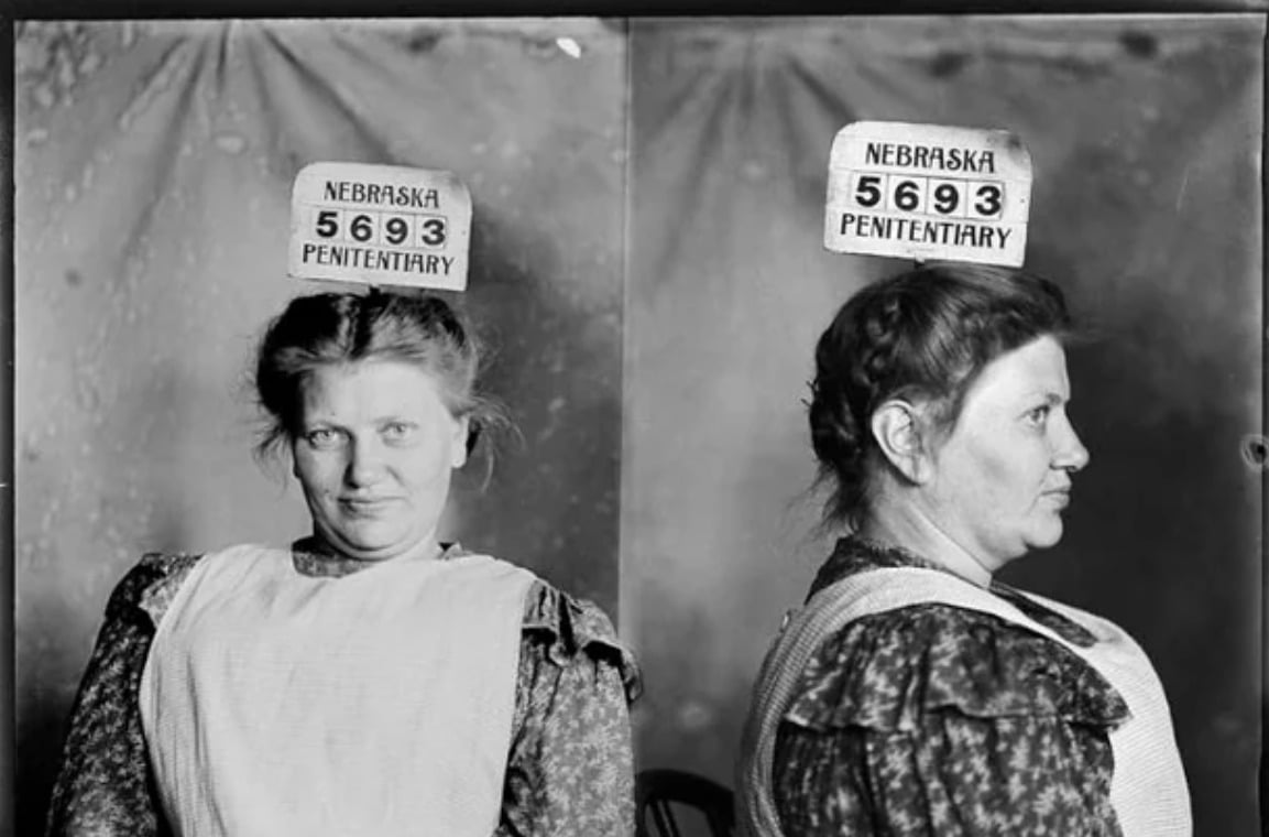 Black-and-white mugshot of a woman wearing a patterned dress and apron, shown facing forward and in profile, with a sign above her head reading "Nebraska Penitentiary 5693.