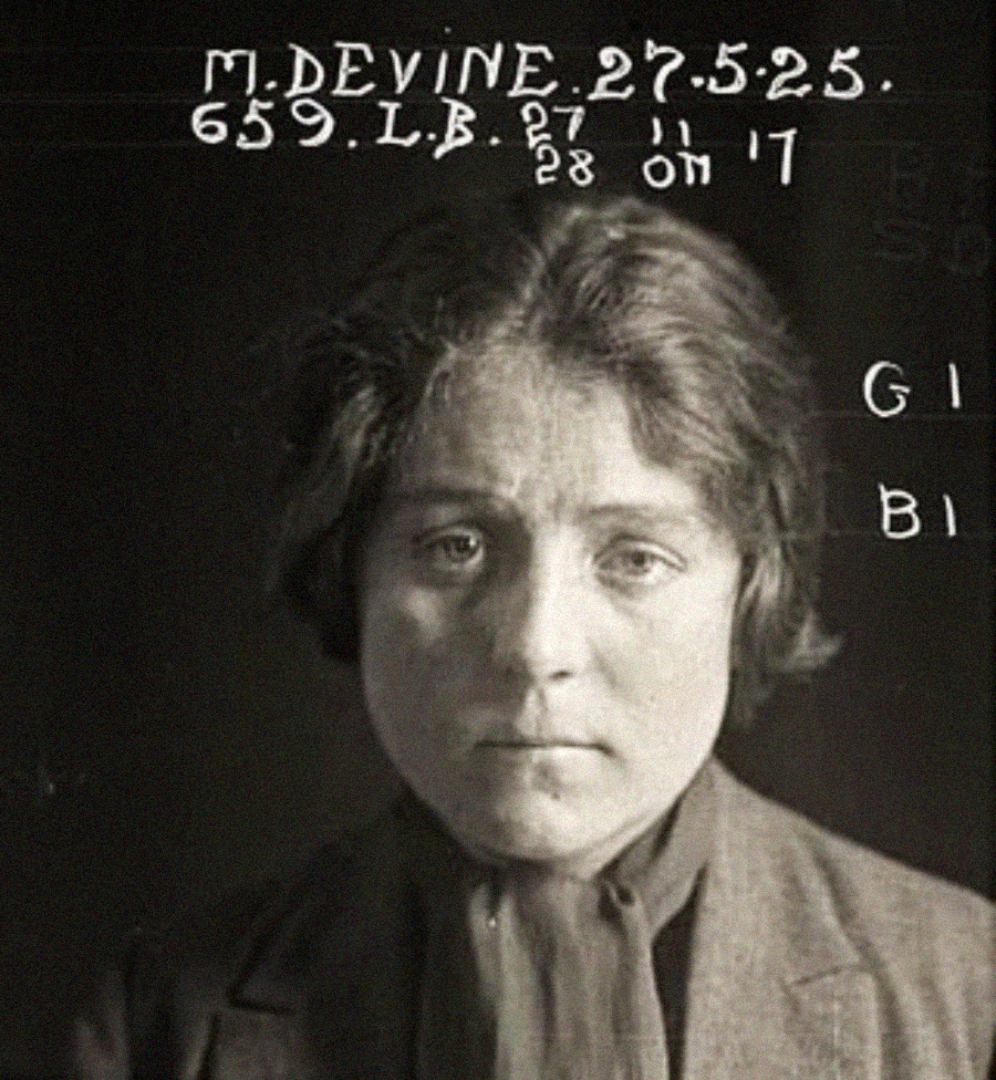 Black-and-white mugshot of a woman with short hair, wearing a dark scarf and jacket, looking slightly downcast. Handwritten text above her head displays her name, date, and identification numbers.