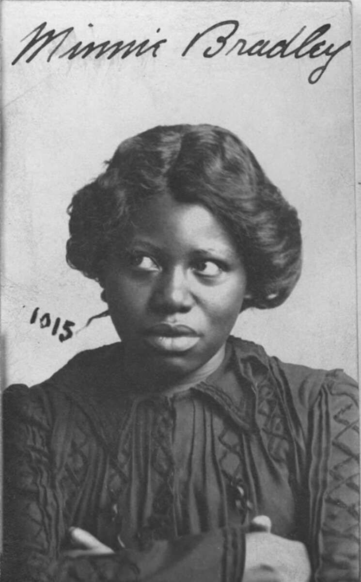 Black and white portrait of a woman with styled hair, wearing a dark, patterned blouse. She looks slightly to her left. The name "Minnie Bradley" is handwritten at the top, with “1015” written on the left side.
