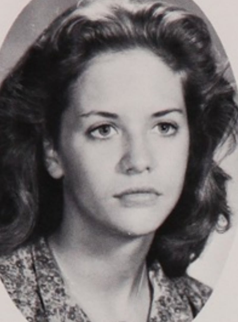 Black and white portrait of a young woman with wavy hair, wearing a patterned blouse, looking slightly past the camera with a calm expression.
