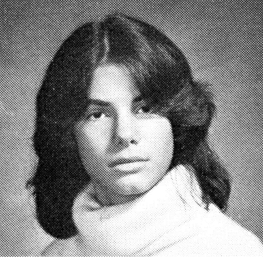 Black and white yearbook-style portrait of a young person with medium-long, dark hair wearing a light-colored turtleneck sweater, looking slightly past the camera with a neutral expression.