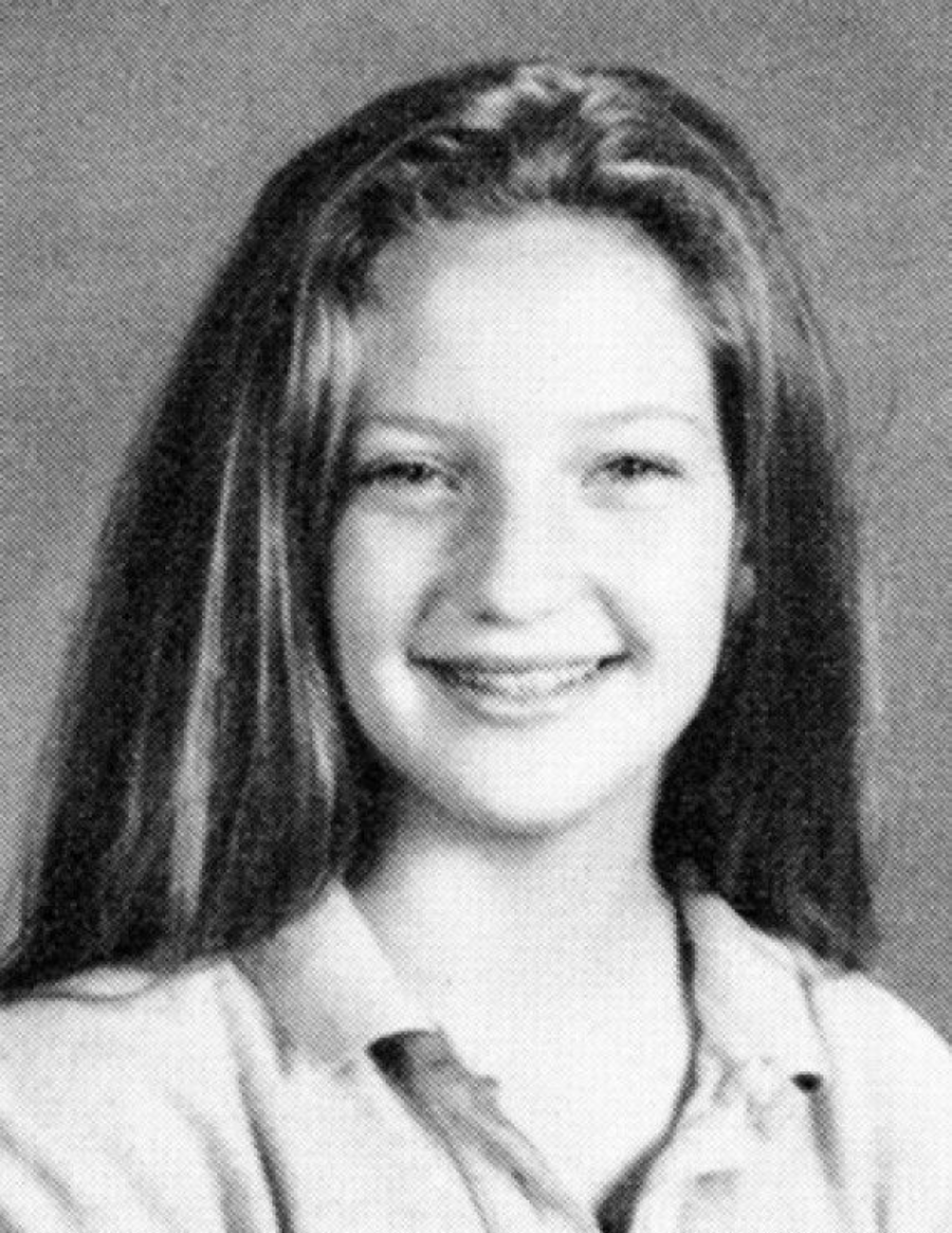 A black and white yearbook-style portrait of a young girl with long straight hair, smiling with visible braces, wearing a collared shirt against a plain background.