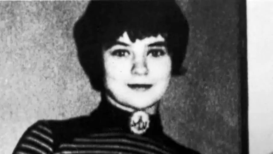 Black and white photo of a young woman with short dark hair, wearing a striped top and a brooch at the collar. She is facing the camera and has a neutral expression.