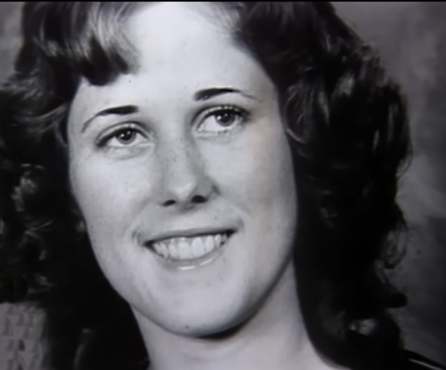 Black and white portrait of a young woman with curly hair, smiling and looking slightly to the side.