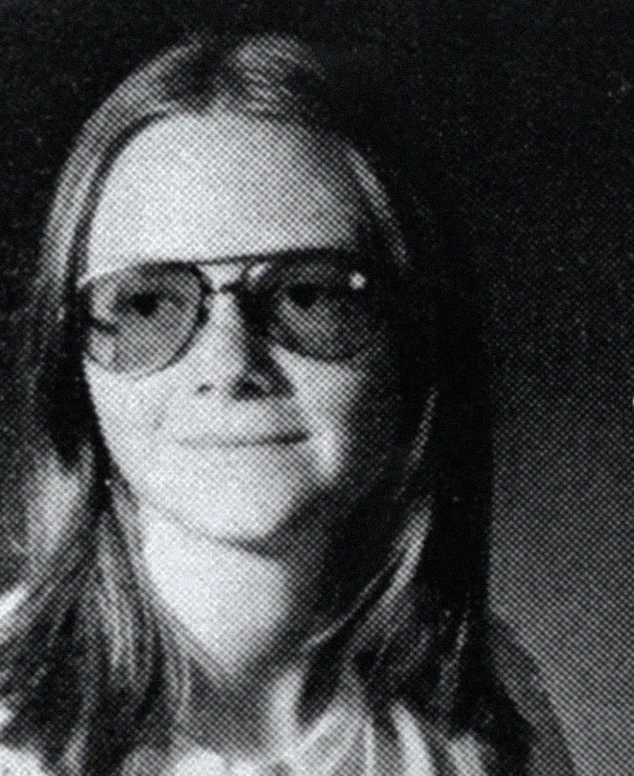 Black and white yearbook-style portrait of a young person with long straight hair, wearing large aviator-style glasses and a slight smile, looking slightly off camera.