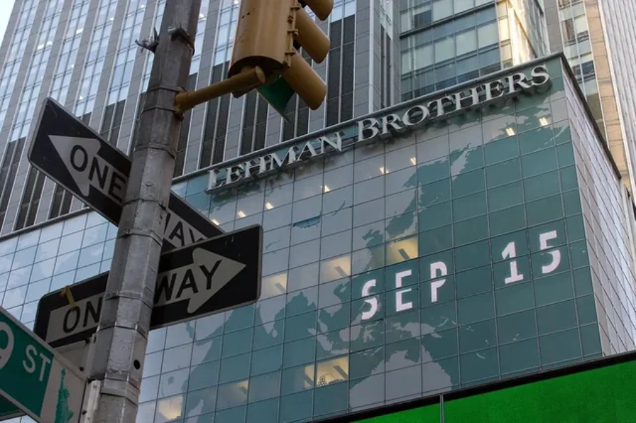 A Lehman Brothers building with a glass facade displays “SEP 15” in large letters. Two one-way street signs and a traffic light are visible in the foreground.