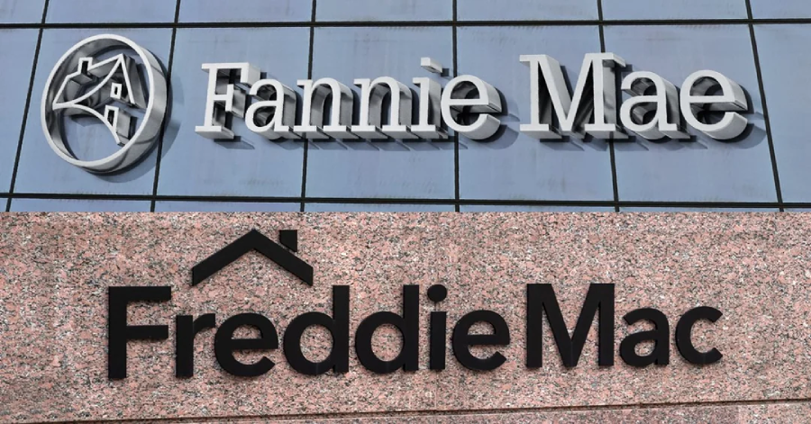 Signs for Fannie Mae and Freddie Mac are displayed on separate building facades. Fannie Mae’s logo appears on glass, while Freddie Mac’s logo is on a stone wall below. Both logos feature stylized house graphics.
