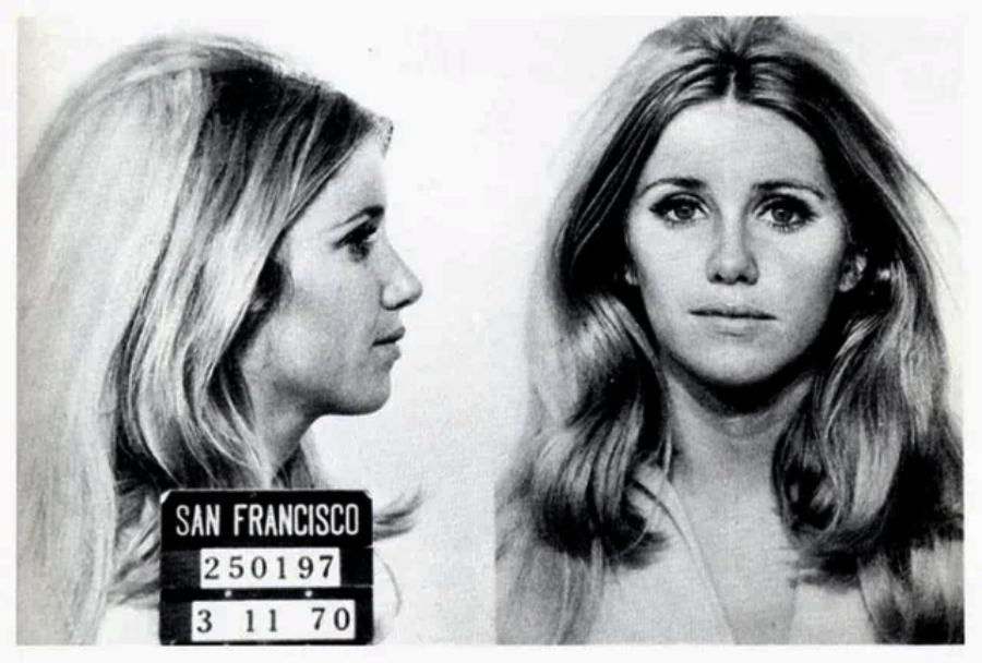 Black-and-white mugshot of a young woman with long, light hair, shown from the side and front. She appears calm. A plaque reads "San Francisco" with the date 3-11-70 and identification numbers.