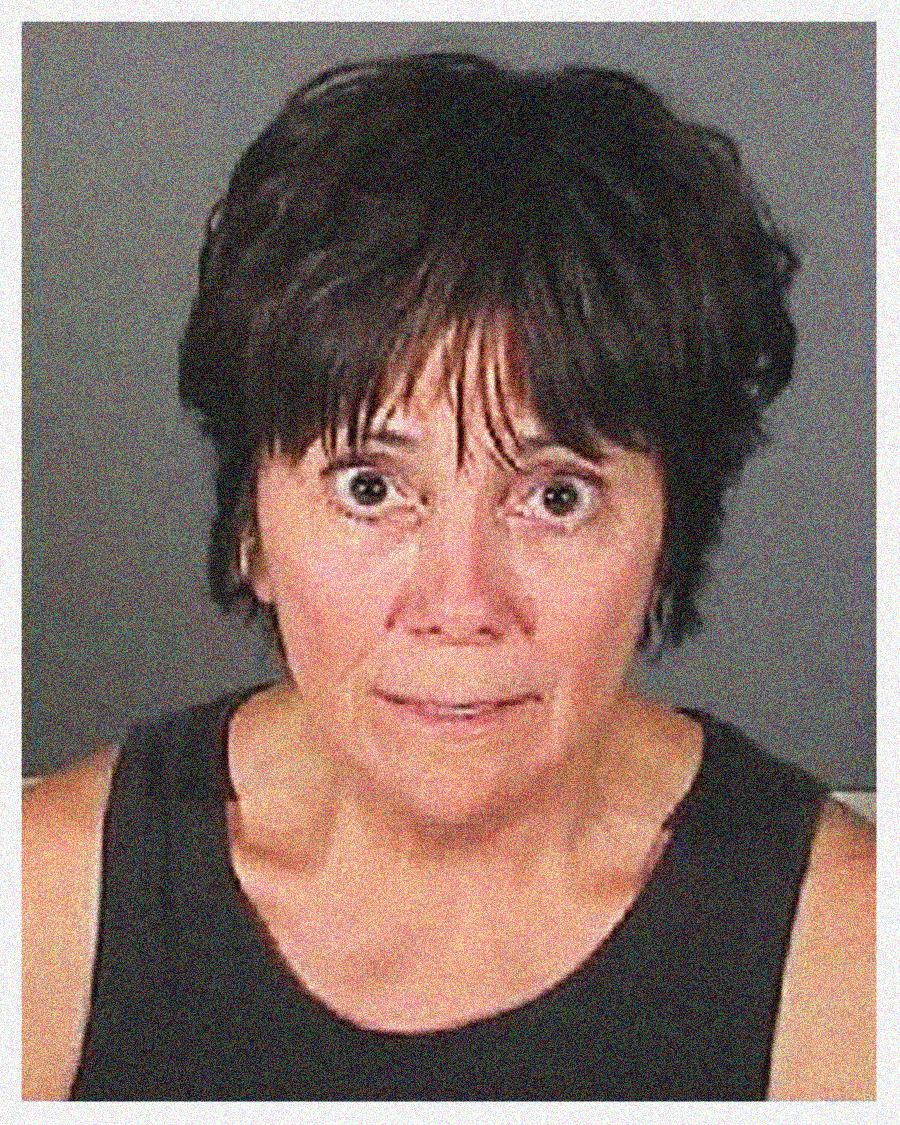 A woman with short dark hair and a concerned expression is wearing a sleeveless black top, shown in a mugshot-style photo against a plain dark background.