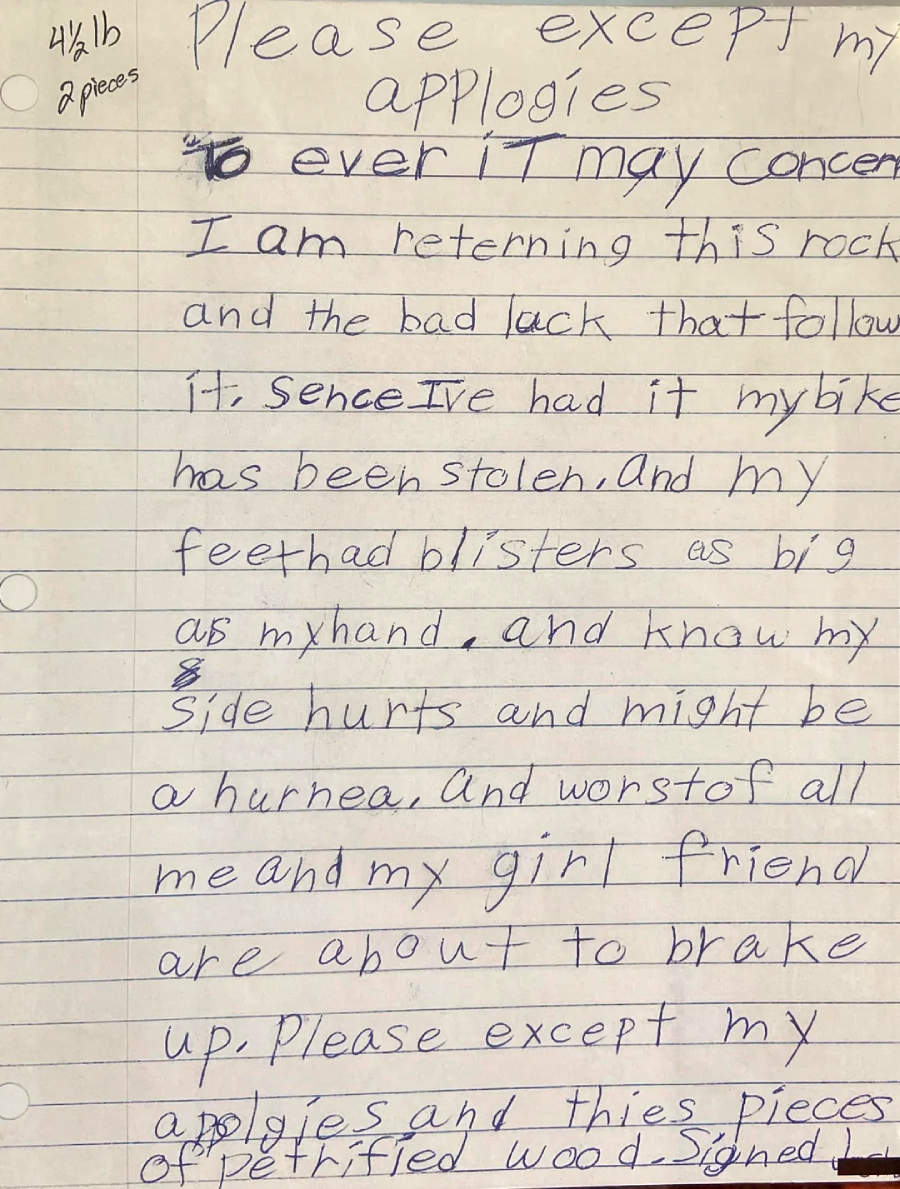 A handwritten letter on lined paper apologizing for returning a rock due to bad luck, injuries, and relationship trouble since acquiring it. It notes, “Please except my apologies,” and is signed as “pieces of petrified wood.”
