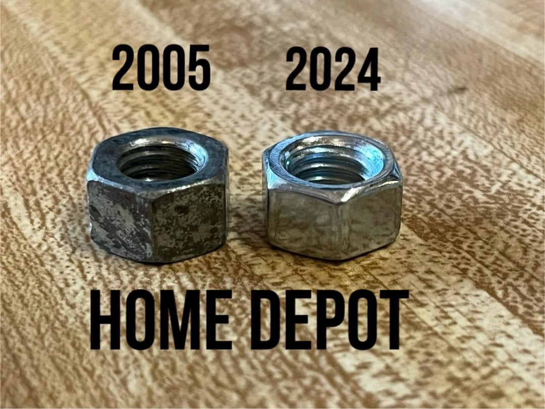 Two metal hex nuts sit side by side on a wooden surface. The left nut is worn and labeled "2005," while the right nut looks new and is labeled "2024." The words "HOME DEPOT" appear below both nuts.