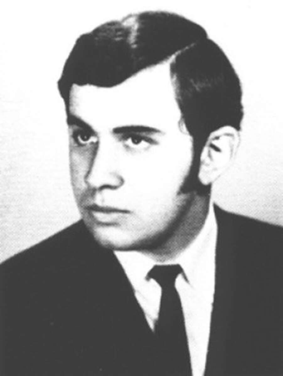 Black-and-white portrait of a young man with short dark hair, wearing a suit and tie, looking slightly to the side with a neutral expression.