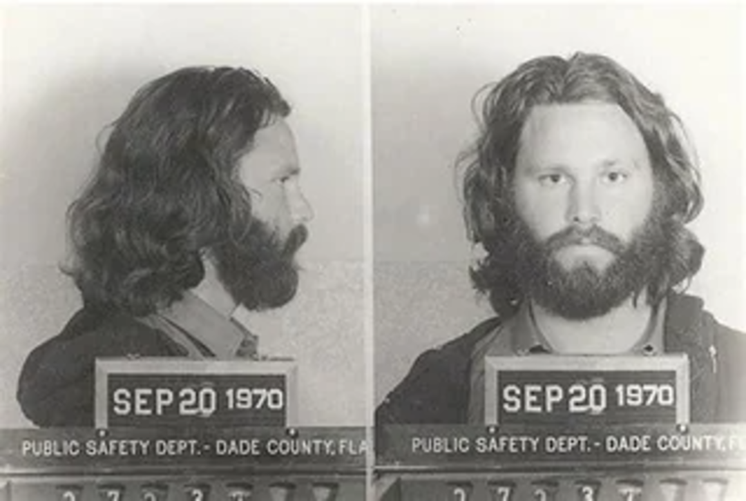 Black and white mugshot of a bearded man with long hair, shown in side and front views, holding a placard with the date September 20, 1970, from the Dade County, Florida Public Safety Department.