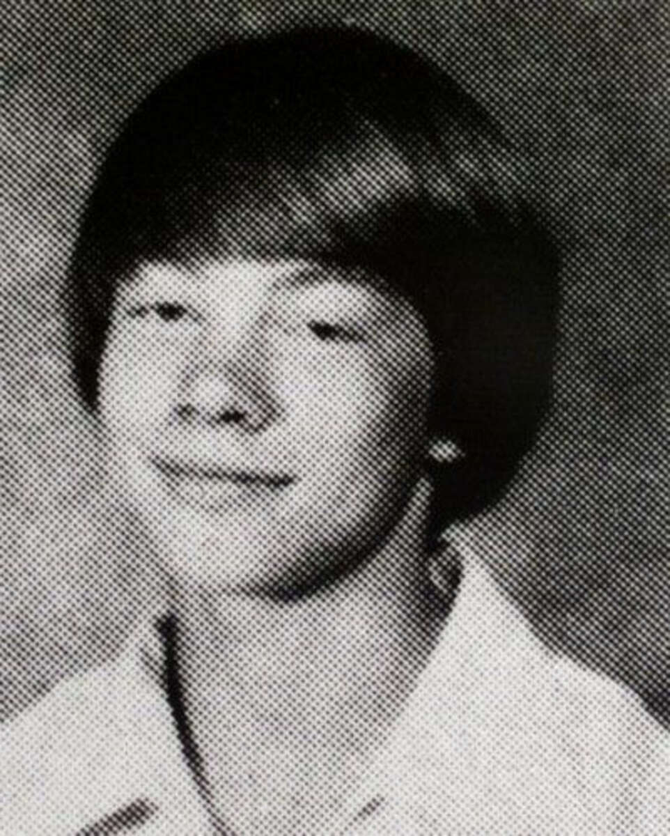 Black-and-white yearbook photo of a young person with straight, medium-length hair, wearing a light-colored collared shirt, and smiling slightly while facing the camera.