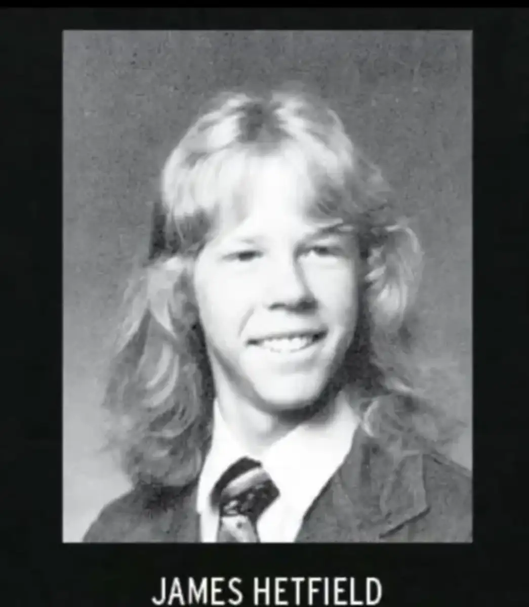 A black-and-white yearbook-style portrait of a young person with long, wavy blonde hair wearing a suit, dress shirt, and tie, smiling at the camera. The name "James Hetfield" appears below the image.