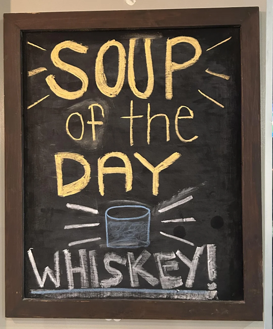 A chalkboard sign reads "Soup of the Day: Whiskey!" in large yellow and white letters, with a drawing of a glass in the center.