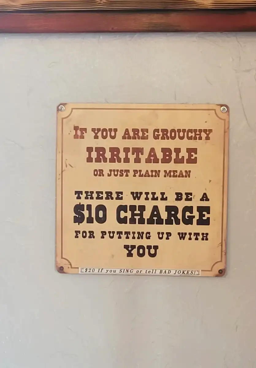A sign reads: "If you are grouchy, irritable, or just plain mean, there will be a $10 charge for putting up with you. $20 if you sing or tell bad jokes!