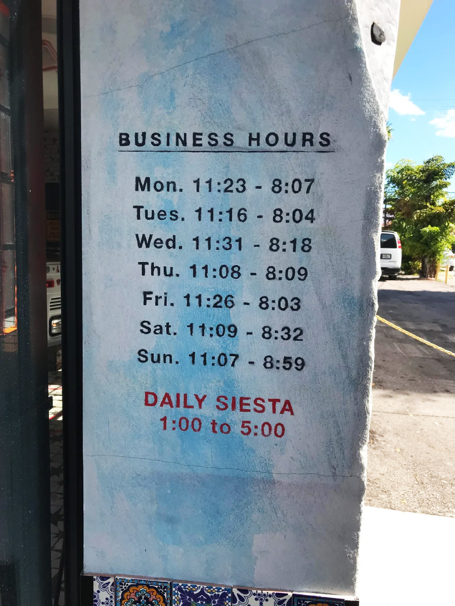 A wall sign displays business hours for each day of the week, with slightly different opening and closing times. It also notes a daily siesta break from 1:00 to 5:00 in red text.