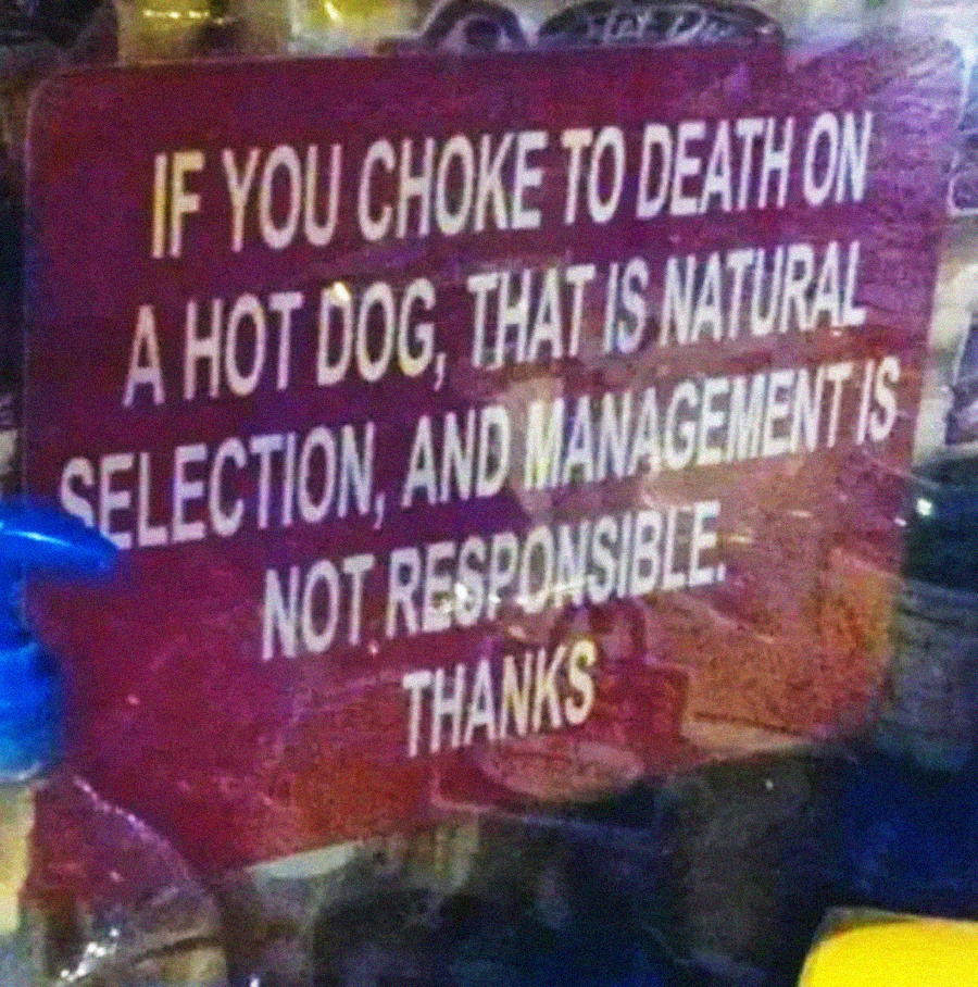 A sign reads: “IF YOU CHOKE TO DEATH ON A HOT DOG, THAT IS NATURAL SELECTION, AND MANAGEMENT IS NOT RESPONSIBLE. THANKS.”