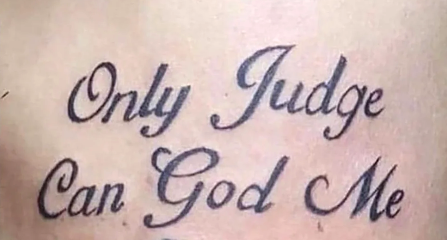 Tattoo with the text "Only Judge Can God Me" in cursive script on skin. The words are written in black ink.