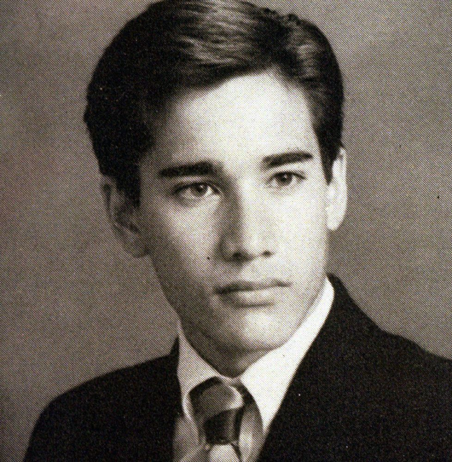 Black and white portrait of a young man with neatly styled dark hair, wearing a suit, dress shirt, and tie, looking slightly to the side with a neutral expression.