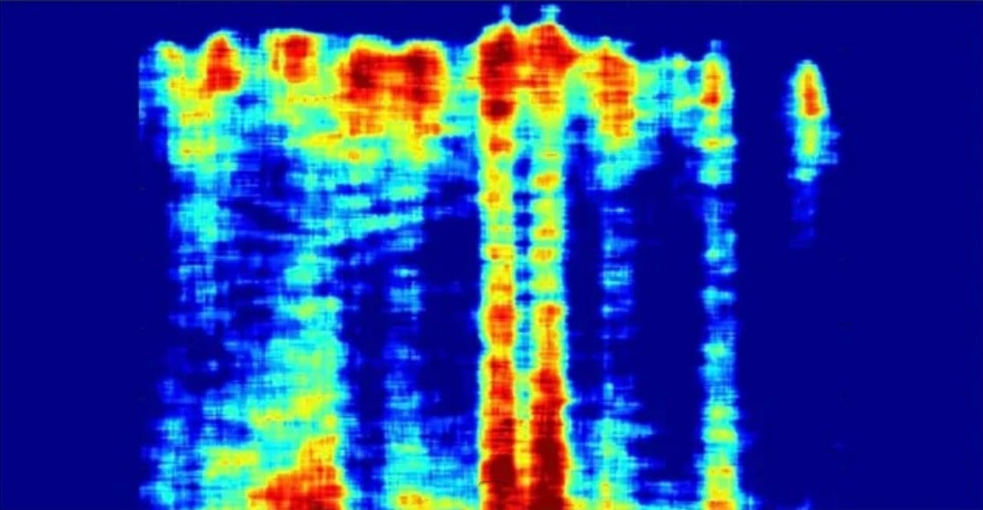 A colorful spectrogram showing vertical bands in red, yellow, and light blue shades against a dark blue background, representing varying intensities of audio frequencies over time.