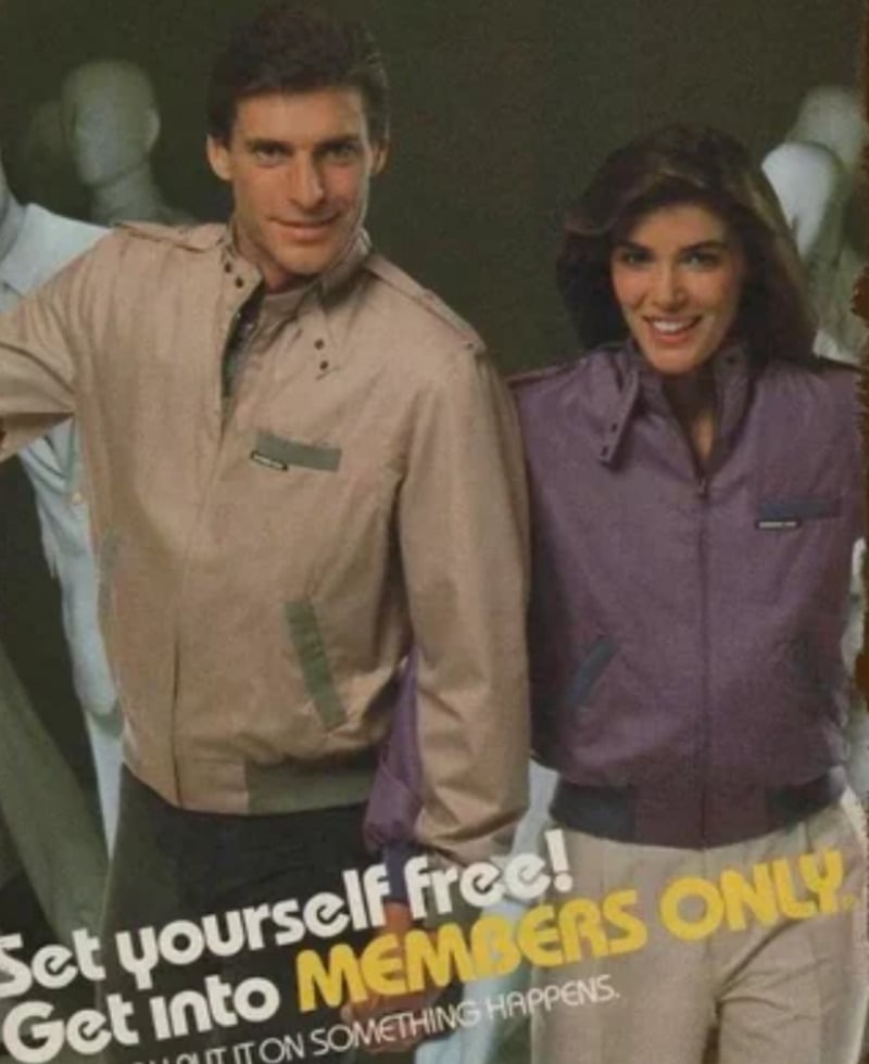 A man and a woman smile while modeling beige and purple Members Only jackets. They stand in front of mannequins, with the text: "Get yourself free! Get into MEMBERS ONLY" overlaid at the bottom.