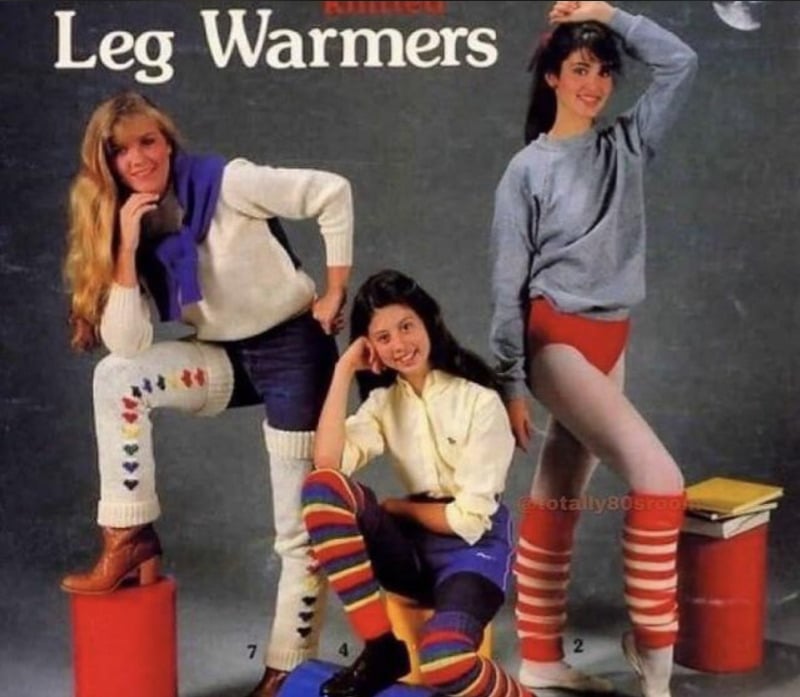 Three women pose in colorful 1980s outfits and leg warmers for a vintage catalog cover titled "Knitted Leg Warmers." Two women stand while one sits, all smiling and showing off various bright, striped leg warmer designs.