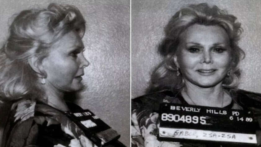 Black and white mugshot of a woman with wavy blonde hair, wearing a floral top, pictured in both side and front profiles. She holds a placard marked "Beverly Hills PD" and identification numbers.