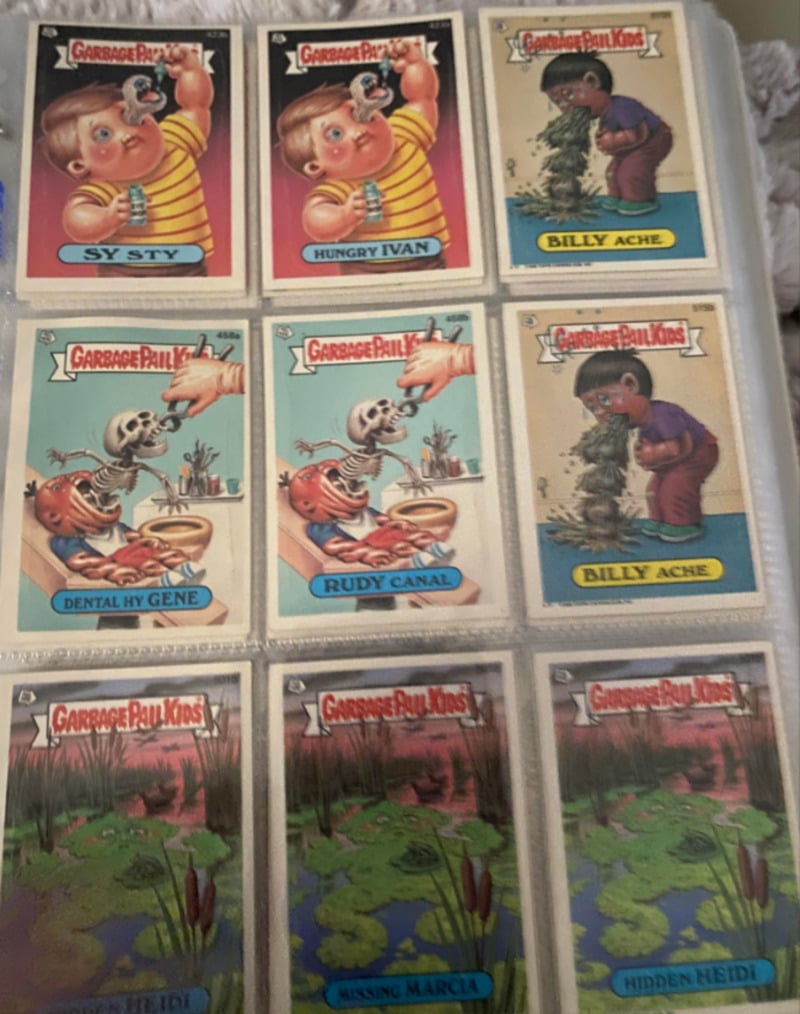 A collection of nine vintage Garbage Pail Kids trading cards in a plastic sleeve, featuring cartoon characters with humorous, grotesque names and exaggerated features.