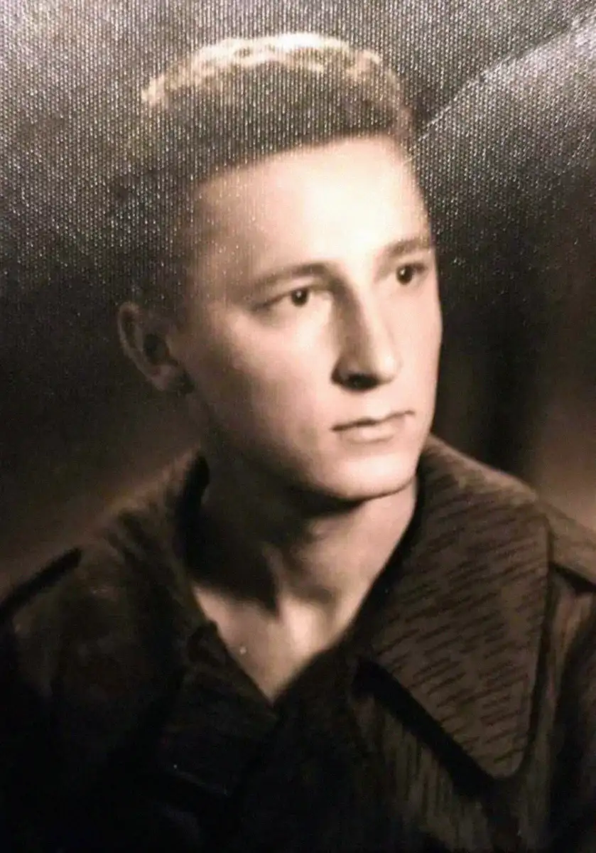 Black and white portrait of a young man with short, neatly styled hair, wearing a collared shirt or jacket, looking slightly to the right with a serious expression.