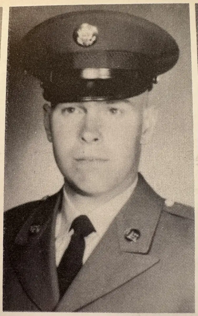 Black-and-white photo of a young man in a military uniform and cap, facing forward with a neutral expression. The image has a textured, slightly grainy quality, typical of older photographs.
