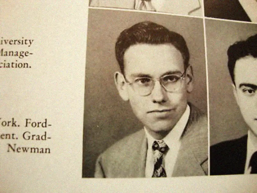 A sepia-toned yearbook photo shows a young man with glasses, short dark hair, and a serious expression, dressed in a suit, tie, and collared shirt. Fragments of text and other portraits frame the image.
