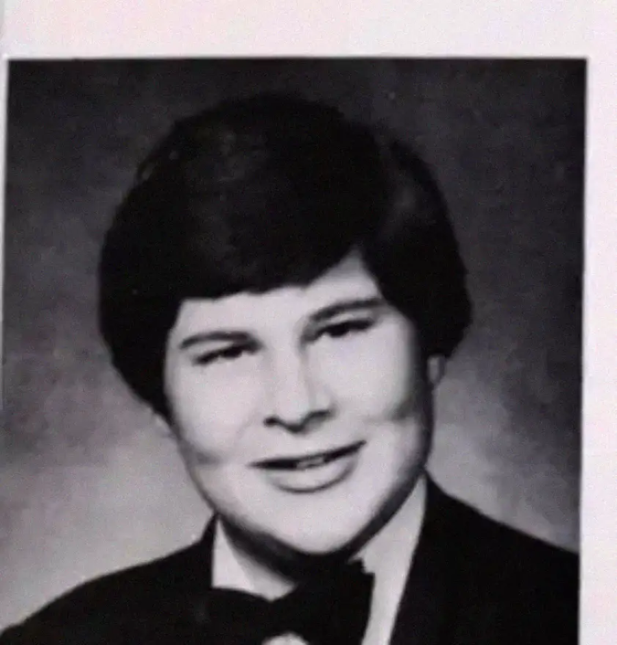 Black and white portrait of a young person with short, dark hair, wearing a tuxedo with a bow tie. The background is plain and the person is smiling slightly.