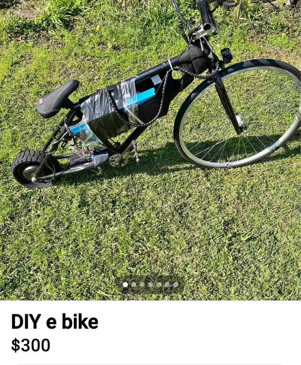 A homemade electric bicycle with a small rear wheel, large front wheel, and battery pack secured to the frame with duct tape, parked on grass. Listing text reads "DIY e bike $300.