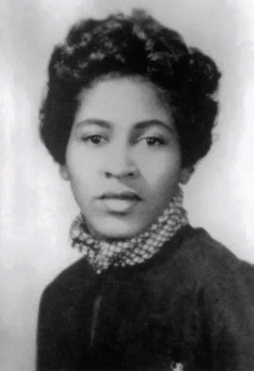 Black and white portrait of a young woman with short, curly hair, wearing a patterned scarf and a dark top, looking slightly to the side with a neutral expression.