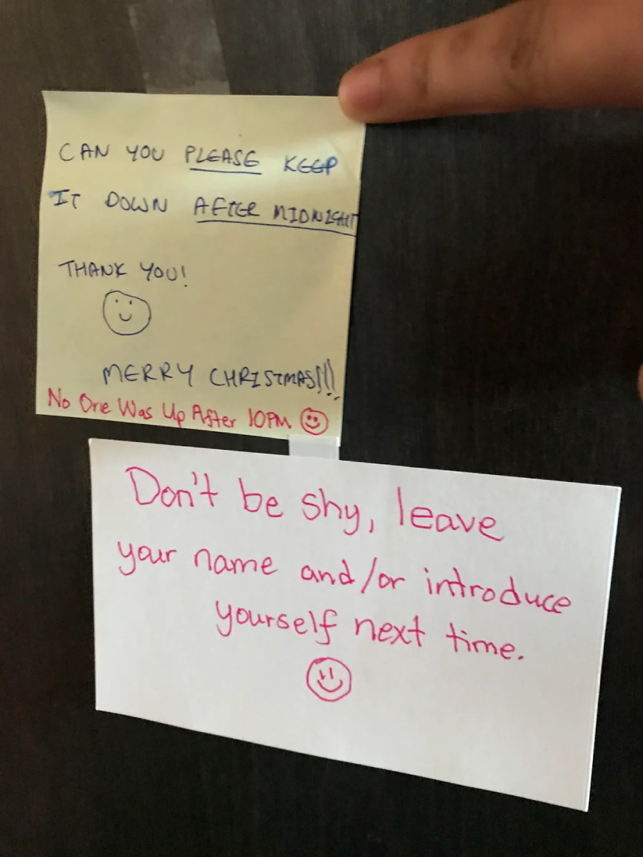 Two notes on a dark surface. The top note politely asks to keep the noise down after midnight and says "Merry Christmas!!" The bottom note requests the reader to leave their name or introduce themselves next time.