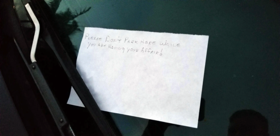A handwritten note under a car windshield wiper reads, "Please don't park here while you are having your affair.