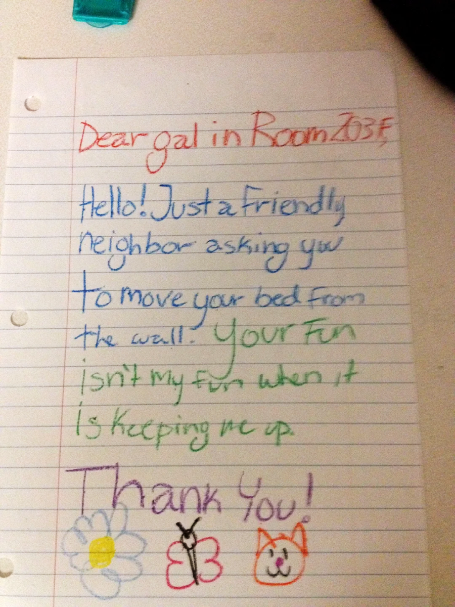A handwritten note on lined paper asks a neighbor to move their bed from the wall because the noise is disruptive. The note ends with “Thank you!” and has drawings of a flower, butterfly, and cat face.