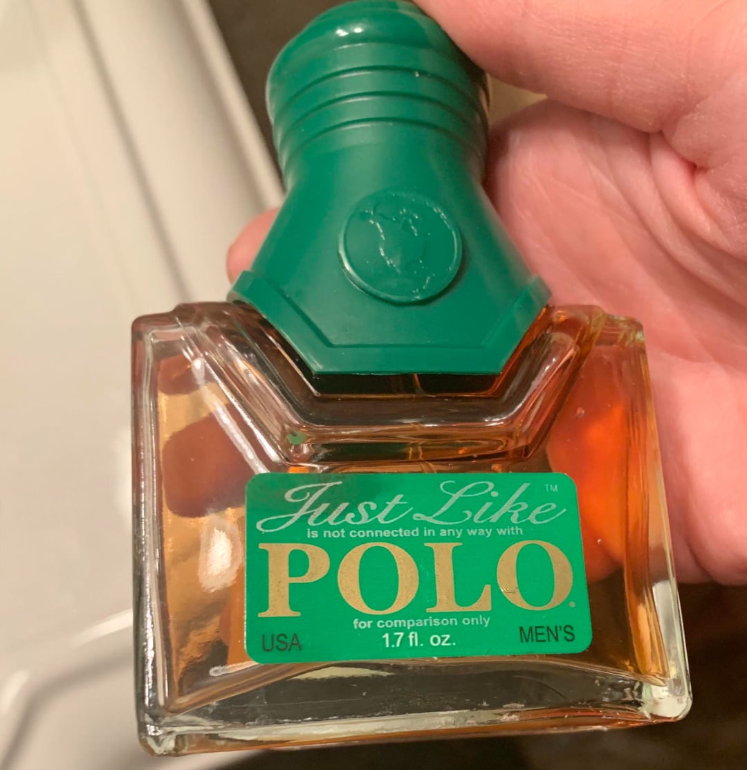 A hand holds a bottle of cologne labeled "Just Like POLO," with a green cap and label stating it is not connected in any way with Polo. The bottle contains 1.7 fl. oz. of men's fragrance.