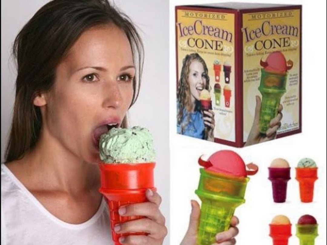 A woman eats mint ice cream from a red motorized ice cream cone holder. The image also shows the product box, which features the product name and multiple images of the motorized cone in different colors with ice cream.