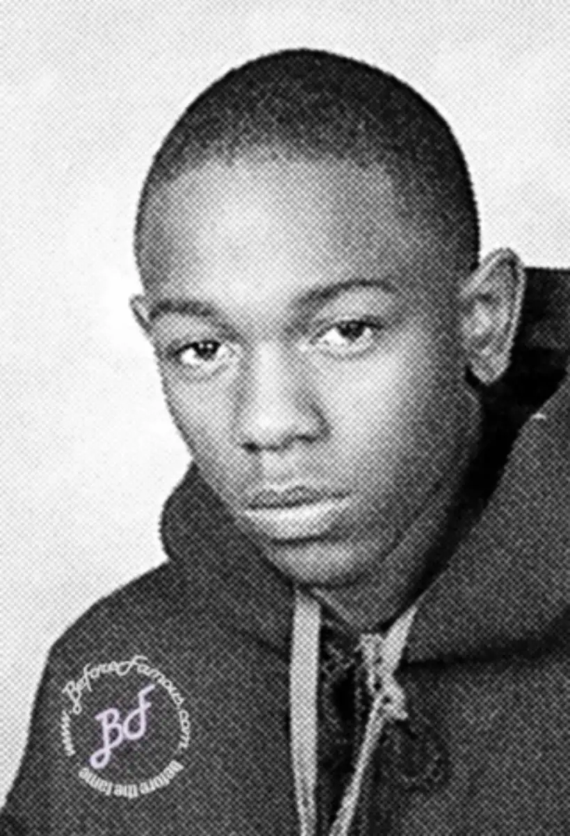 A black and white yearbook-style photo of a young person with close-cropped hair, wearing a hoodie, looking directly at the camera with a neutral expression. There is a watermark in the bottom left corner.