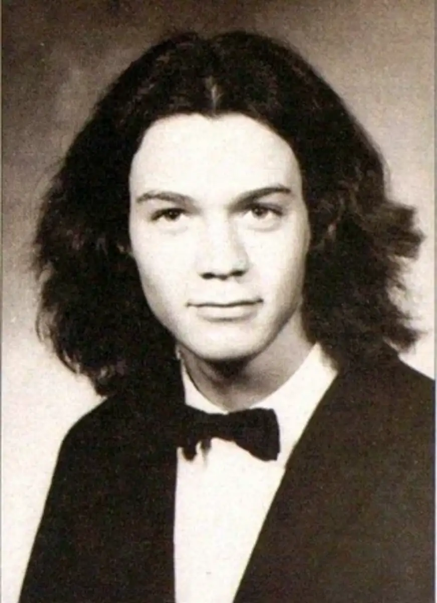 A young person with shoulder-length dark hair, wearing a black tuxedo jacket, white shirt, and black bow tie, poses for a formal black-and-white portrait, likely a school yearbook photo.