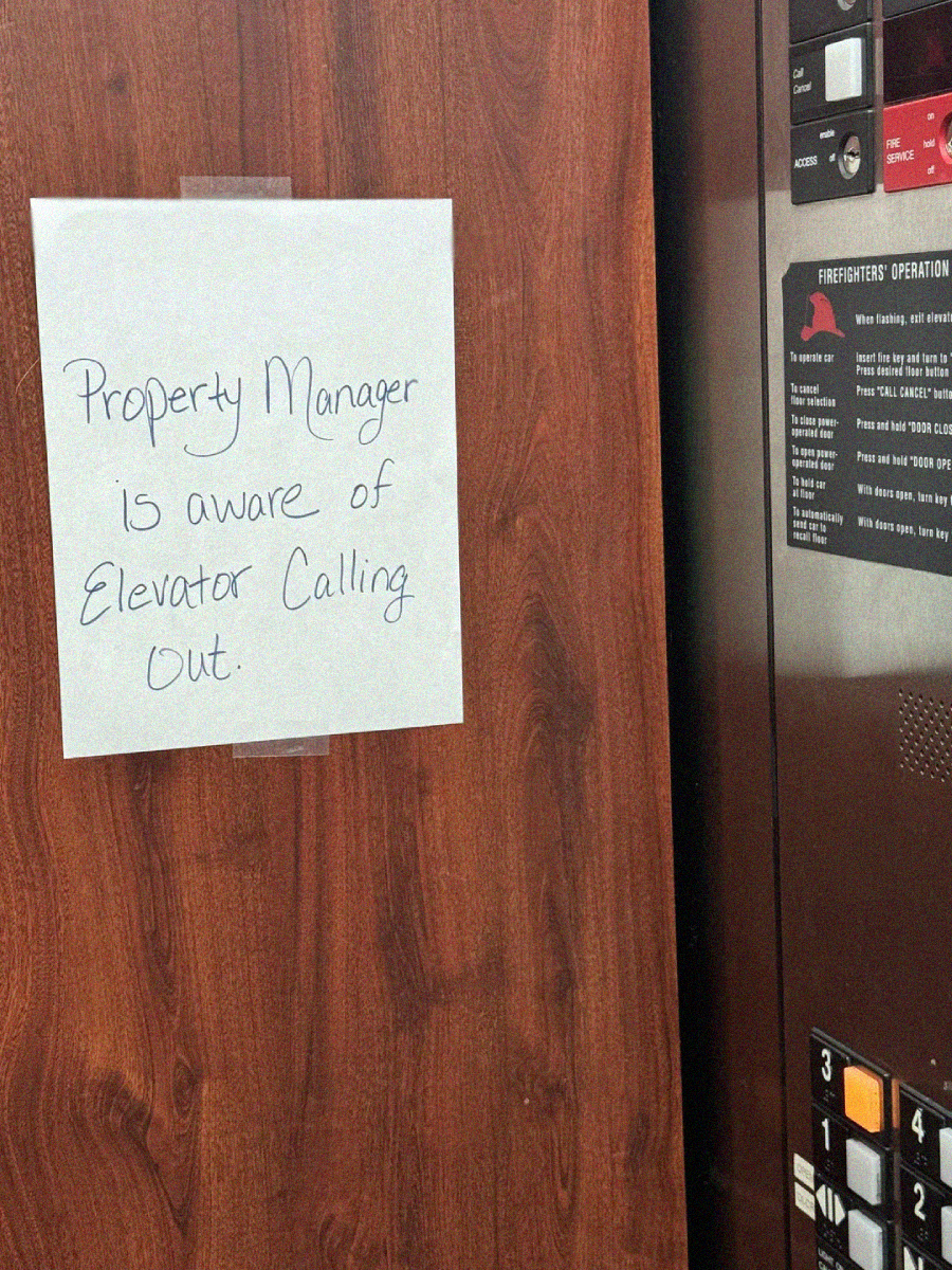A handwritten sign taped on wood panel reads, "Property Manager is aware of Elevator Calling Out." Elevator control buttons and instructions are visible to the right.