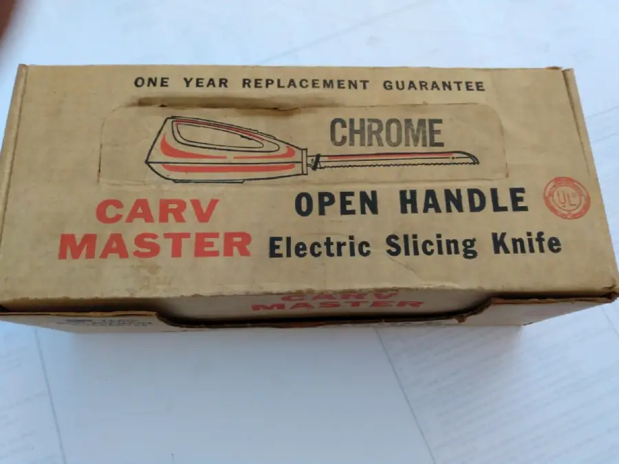 A vintage cardboard box for a Carv Master Chrome Open Handle Electric Slicing Knife, featuring bold black and red text and a simple illustration of the knife on the lid.