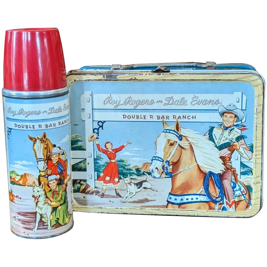 Vintage Roy Rogers and Dale Evans lunchbox and thermos set, featuring colorful illustrations of Roy on a horse, Dale waving, and a dog at Double R Bar Ranch, with a western landscape in the background.