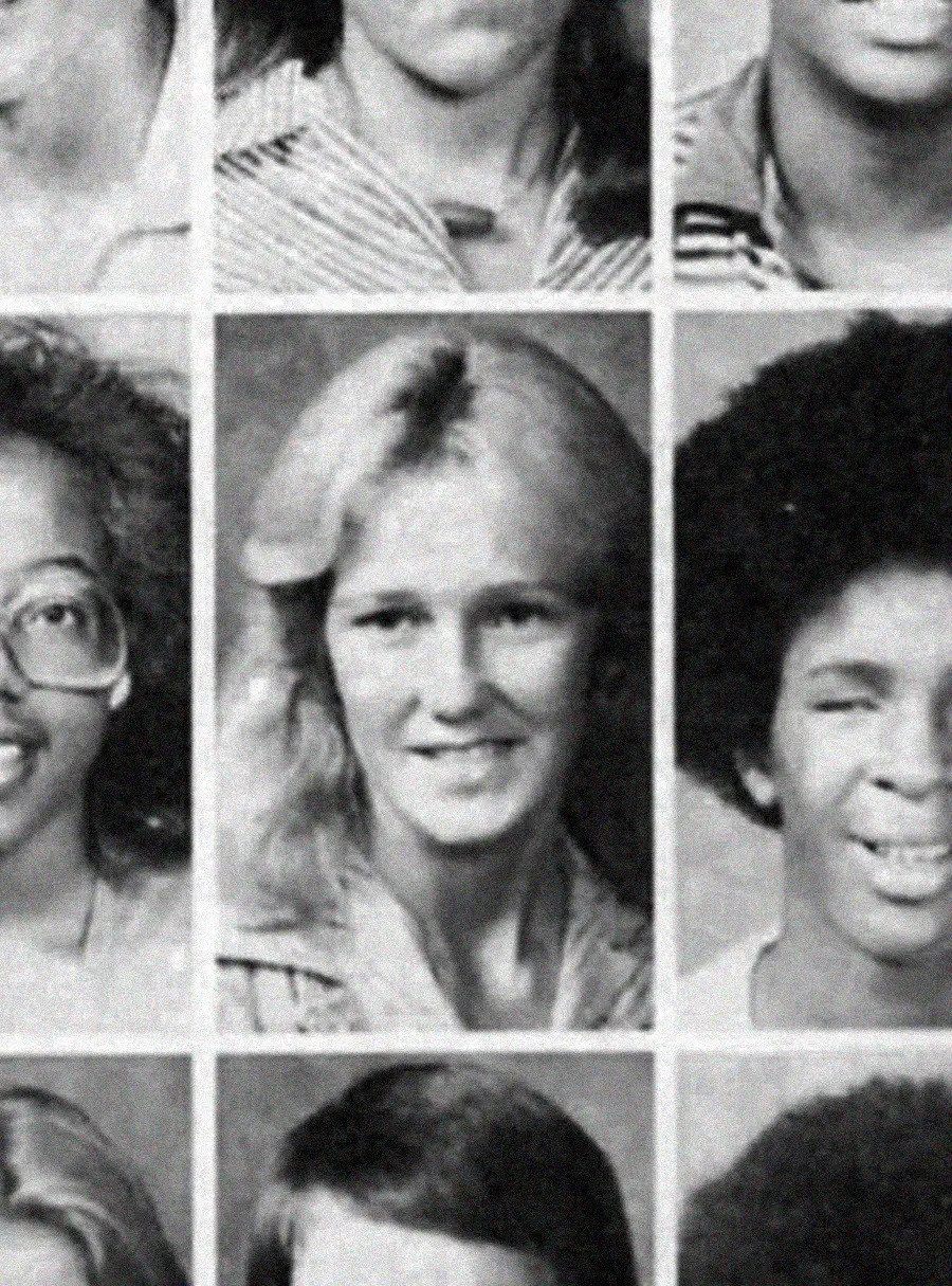 A black-and-white yearbook photo showing a young woman with light hair in the center, surrounded by other students’ portraits. She is smiling slightly and wearing a collared shirt.